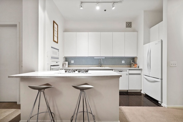 kitchen featuring white cabinetry, a breakfast bar area, a center island, white appliances, and sink