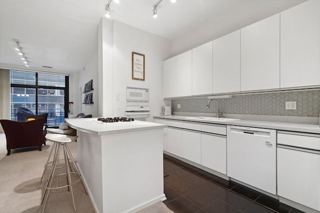 kitchen featuring sink, white cabinets, tasteful backsplash, and white appliances