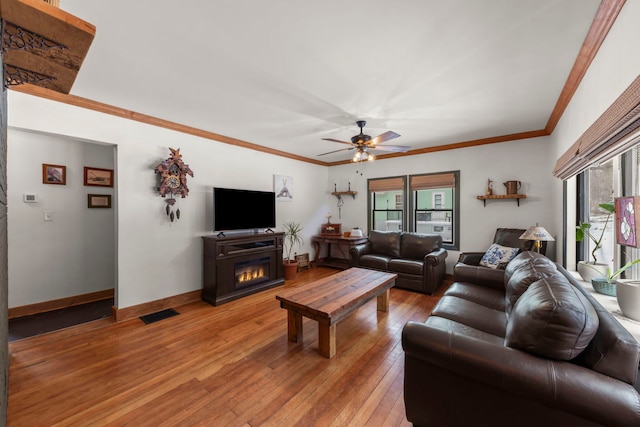 living room with crown molding, ceiling fan, and light hardwood / wood-style floors