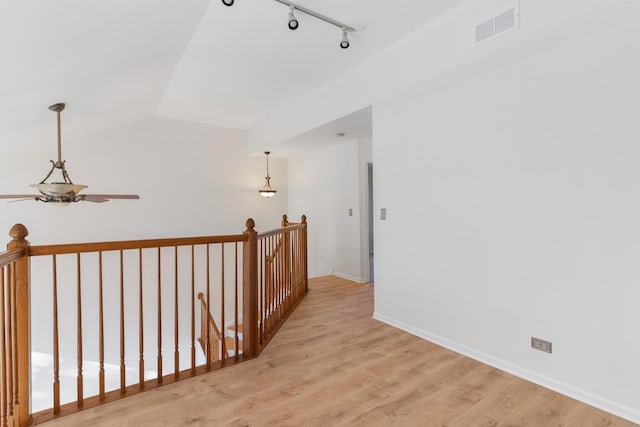 hall with track lighting, light hardwood / wood-style floors, and vaulted ceiling