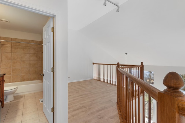 hallway with lofted ceiling and light tile patterned flooring