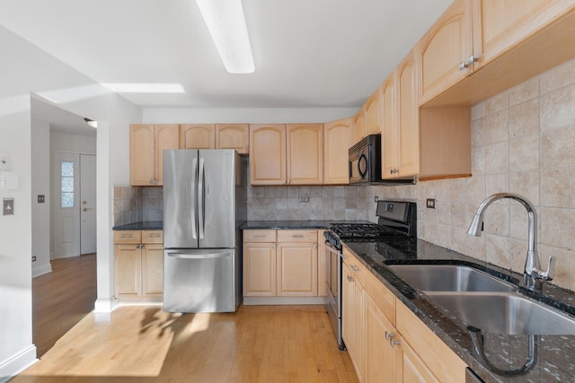 kitchen featuring appliances with stainless steel finishes, light brown cabinetry, sink, and backsplash