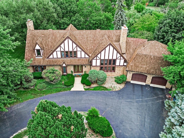 exterior space featuring a garage, aphalt driveway, a chimney, and brick siding