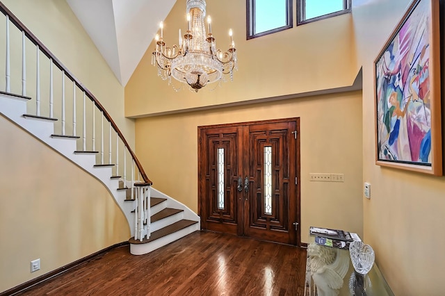 entrance foyer with stairs, an inviting chandelier, wood finished floors, and high vaulted ceiling