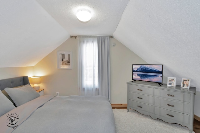 carpeted bedroom featuring a textured ceiling and lofted ceiling