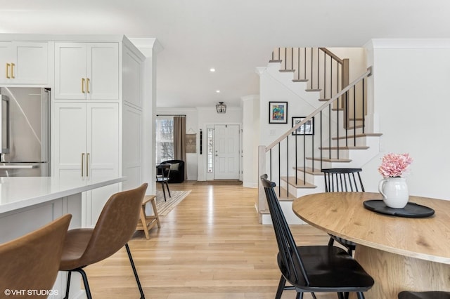 dining space with crown molding and light hardwood / wood-style flooring