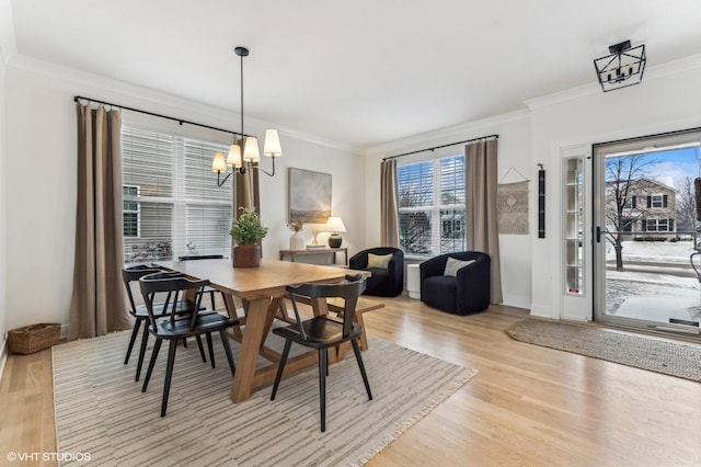 dining space with ornamental molding, a notable chandelier, and light wood-type flooring