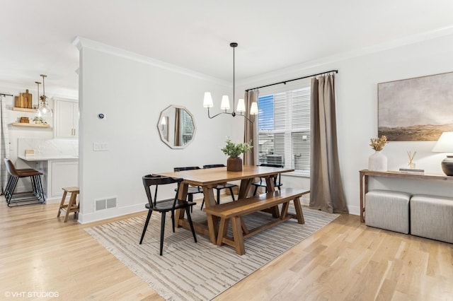 dining space featuring light hardwood / wood-style flooring, an inviting chandelier, and crown molding