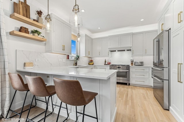 kitchen featuring kitchen peninsula, pendant lighting, a breakfast bar, backsplash, and high quality appliances