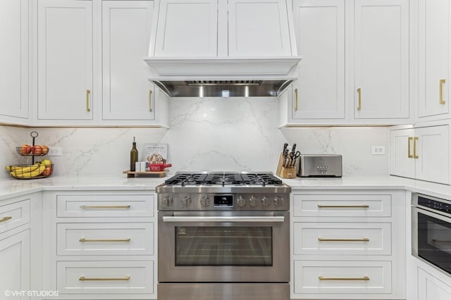 kitchen featuring premium range hood, backsplash, white cabinets, and appliances with stainless steel finishes