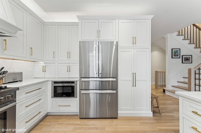 kitchen with light wood-type flooring, white cabinets, and appliances with stainless steel finishes