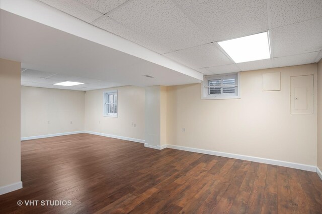 basement featuring a paneled ceiling and dark hardwood / wood-style flooring