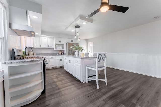 kitchen with decorative light fixtures, dark hardwood / wood-style floors, a kitchen island, light stone countertops, and white cabinets