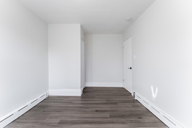 empty room with dark wood-type flooring and a baseboard radiator