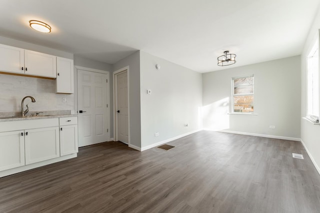 kitchen with decorative backsplash, dark wood-type flooring, sink, and white cabinetry