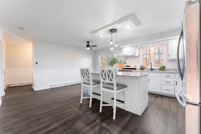 kitchen featuring ceiling fan, stainless steel appliances, hanging light fixtures, a kitchen island, and white cabinets