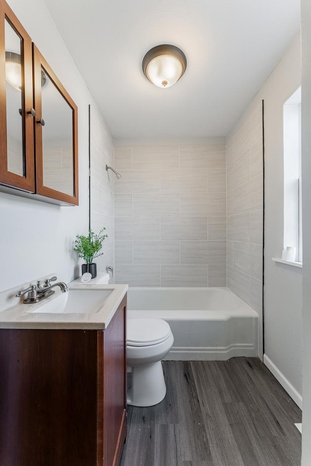 full bathroom with toilet, tiled shower / bath, wood-type flooring, and vanity