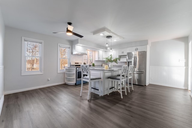 kitchen with stainless steel appliances, decorative light fixtures, a kitchen breakfast bar, white cabinets, and a center island