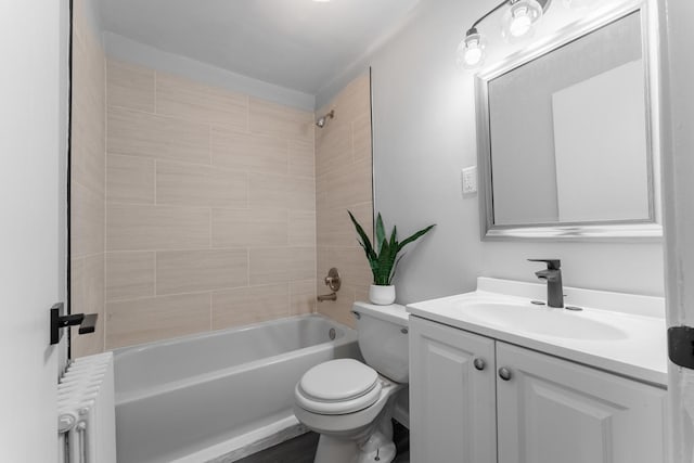 full bathroom featuring toilet, radiator, tiled shower / bath combo, and vanity