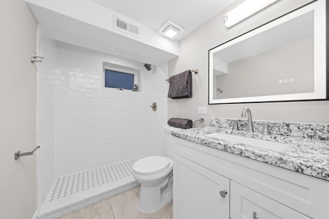 bathroom featuring toilet, vanity, and a tile shower