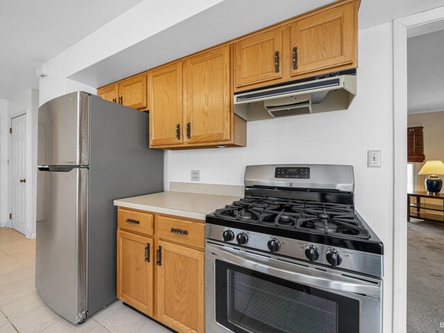 kitchen with brown cabinets, under cabinet range hood, appliances with stainless steel finishes, light countertops, and light tile patterned floors