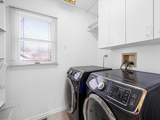 clothes washing area featuring cabinet space, light tile patterned floors, washing machine and dryer, and baseboards