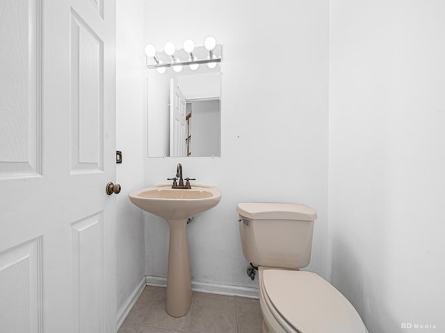 bathroom featuring a sink, baseboards, toilet, and tile patterned flooring