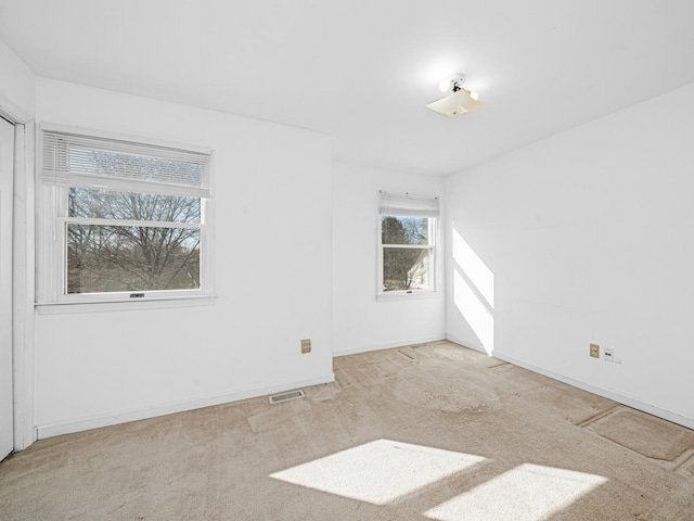 carpeted spare room featuring visible vents and baseboards