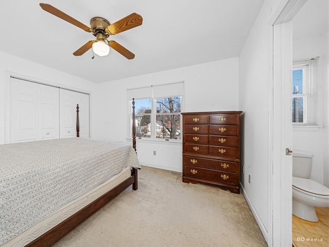 bedroom with a closet, baseboards, light colored carpet, and a ceiling fan