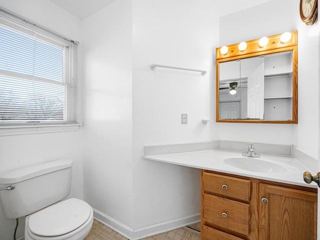 half bathroom featuring vanity, toilet, and baseboards