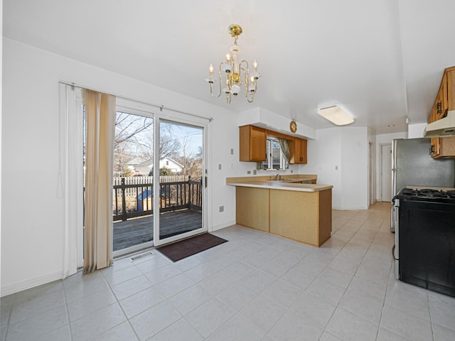 kitchen featuring under cabinet range hood, a sink, gas range oven, a peninsula, and light countertops