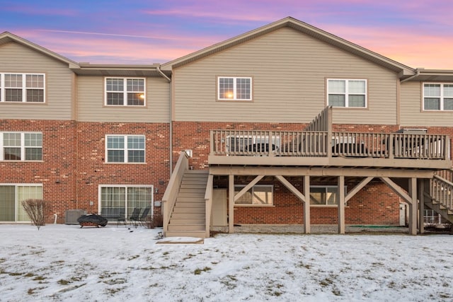 snow covered back of property with a deck