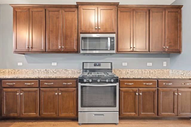 kitchen featuring stainless steel appliances, light stone countertops, and light hardwood / wood-style flooring