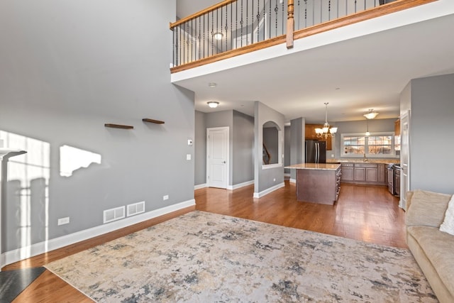 living room featuring dark hardwood / wood-style flooring, a chandelier, sink, and a high ceiling