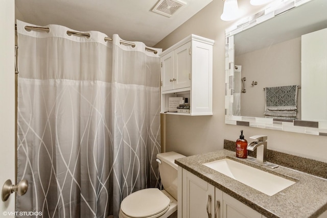 bathroom featuring toilet, vanity, and walk in shower