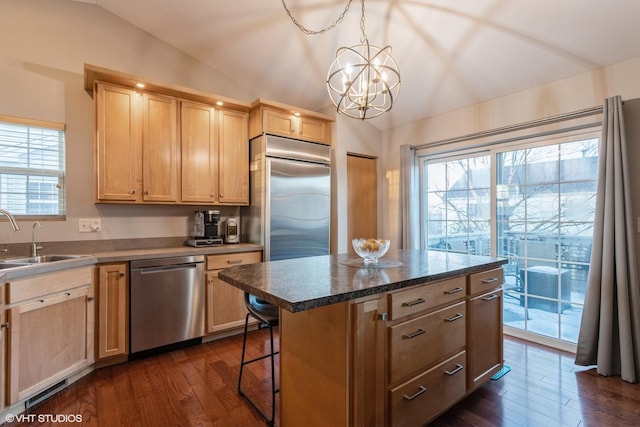 kitchen with a center island, lofted ceiling, light brown cabinets, stainless steel appliances, and a chandelier