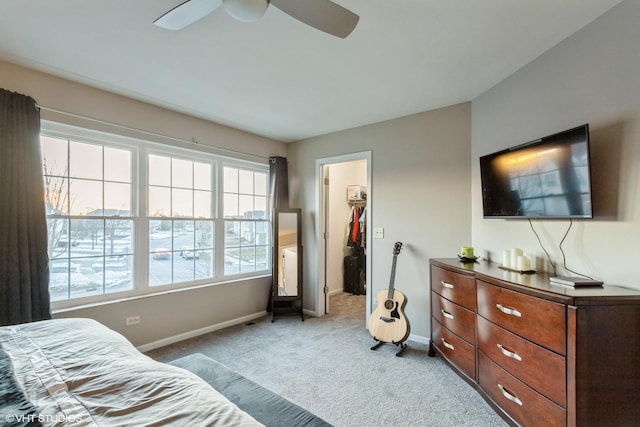 bedroom with ceiling fan, a walk in closet, a closet, and light colored carpet