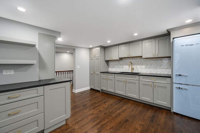 kitchen with dark wood-type flooring, white refrigerator, tasteful backsplash, sink, and gray cabinets