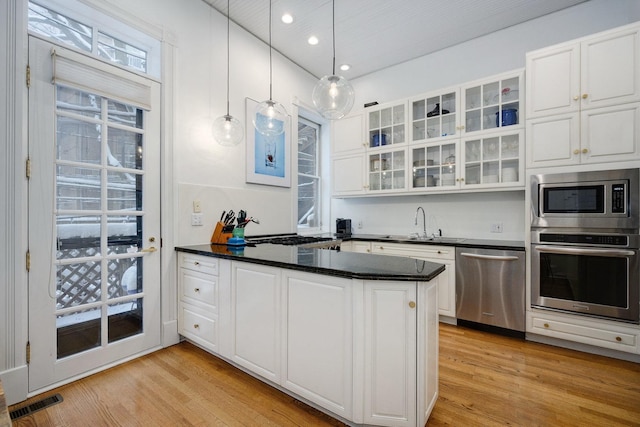 kitchen featuring white cabinetry, stainless steel appliances, pendant lighting, light hardwood / wood-style flooring, and sink