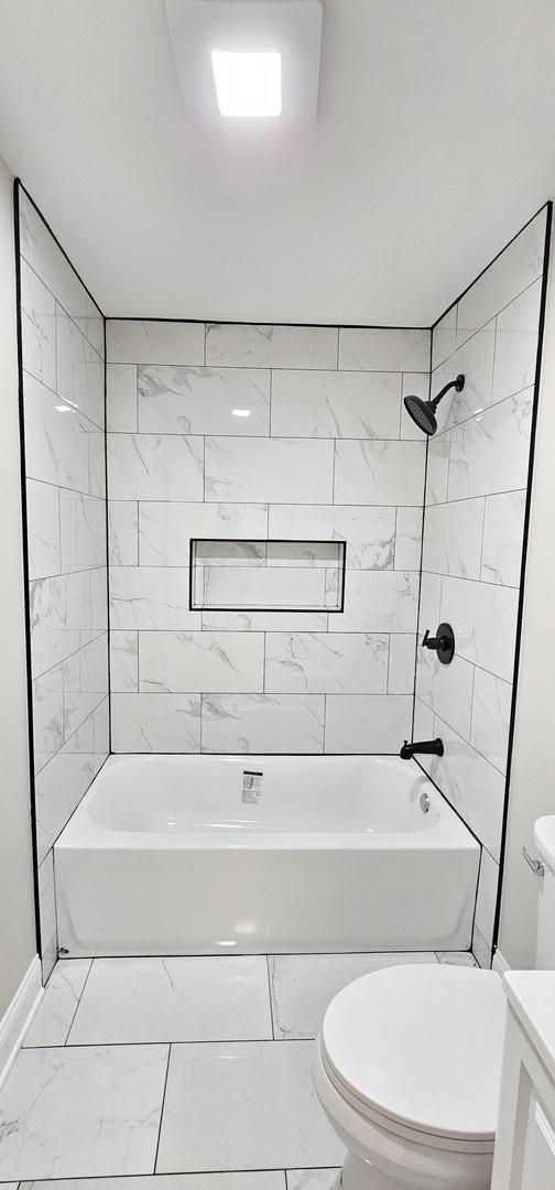 full bathroom with tiled shower / bath combo, vanity, and toilet