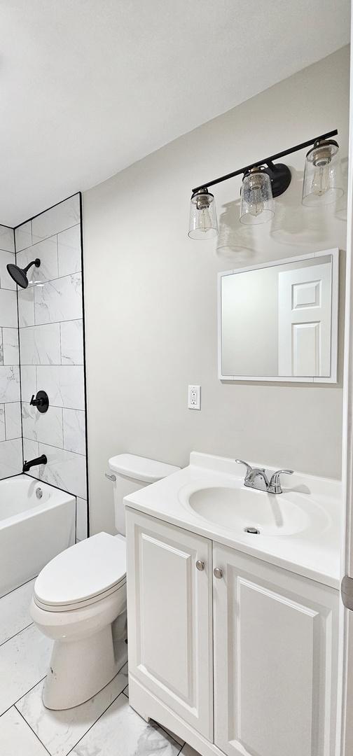 full bathroom featuring toilet, tiled shower / bath, and vanity