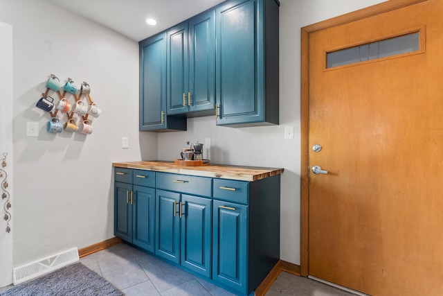 kitchen featuring blue cabinetry, butcher block counters, and light tile patterned floors