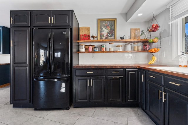 kitchen featuring black fridge, light tile patterned floors, and backsplash