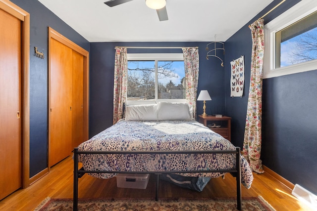 bedroom featuring multiple windows, hardwood / wood-style floors, and ceiling fan