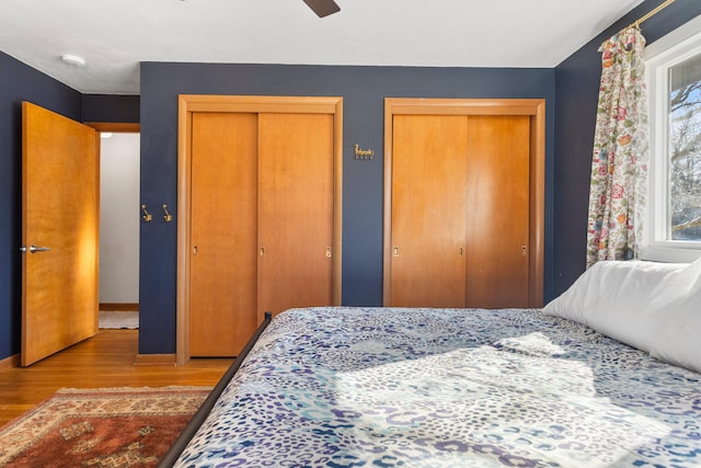 bedroom featuring two closets, light hardwood / wood-style floors, and ceiling fan