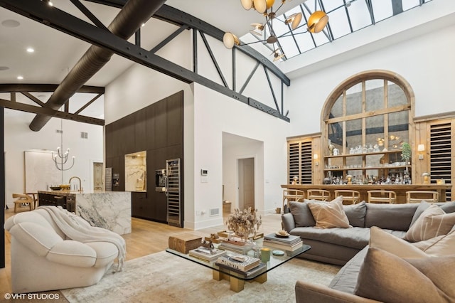 living room with a notable chandelier, light wood-type flooring, and a high ceiling