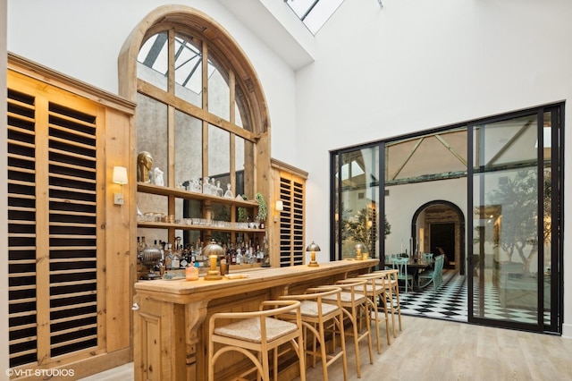 bar featuring hardwood / wood-style flooring and a high ceiling