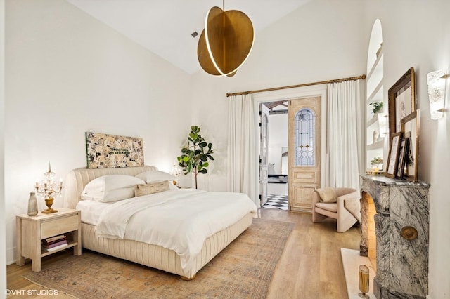 bedroom with high vaulted ceiling and light wood-type flooring