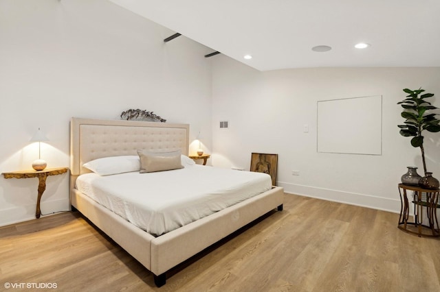 bedroom with wood-type flooring and vaulted ceiling