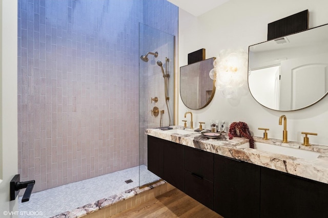 bathroom with hardwood / wood-style flooring, vanity, and a tile shower